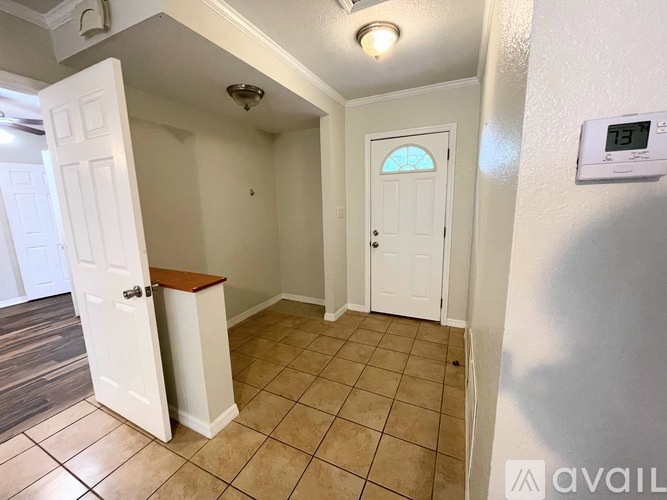 A hallway with a tiled floor and a digital clock on the wall.