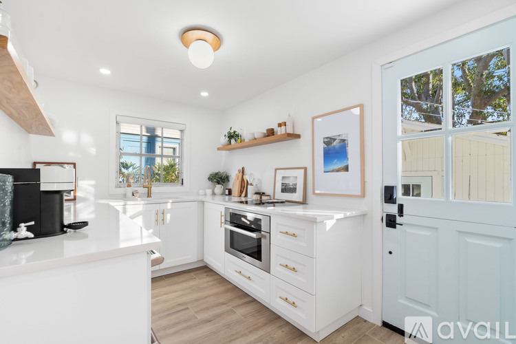 A modern kitchen with white cabinets and a wooden floor.