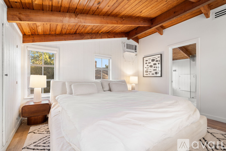 A bedroom with a large bed and a wooden ceiling.
