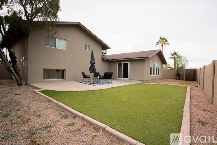 A house with a brown exterior and a green lawn in front.