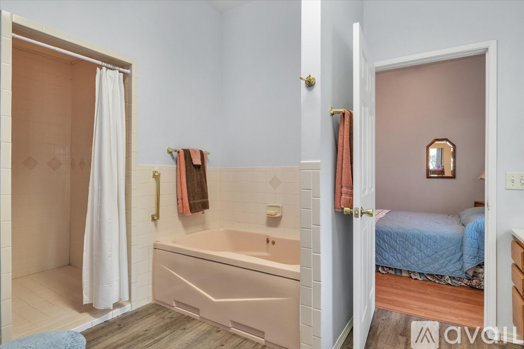 A bathroom with a tub and a bedroom with a bed.