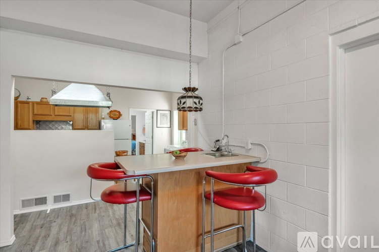 A kitchen with a white counter and red barstools.