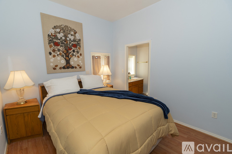 A bedroom with a large bed and a painting of a tree on the wall.