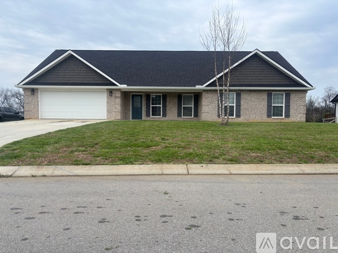 A house with a grey roof and a tree in front of it.