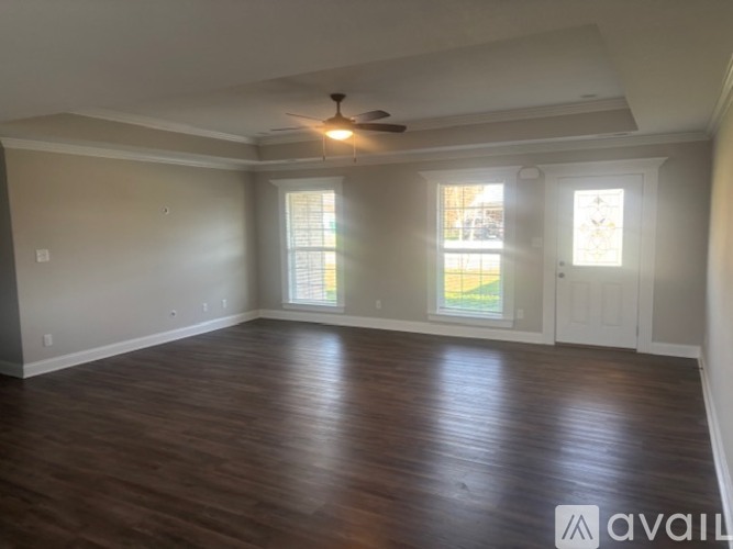 A spacious room with wooden flooring and a ceiling fan.