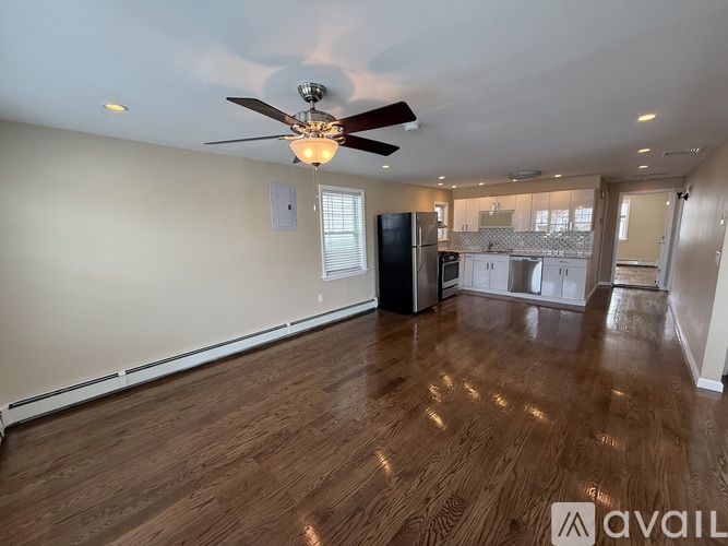 A spacious room with a ceiling fan and wooden flooring.