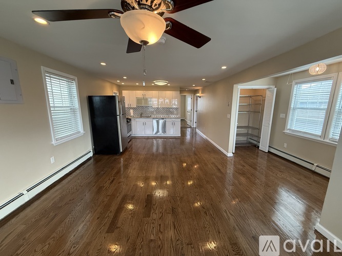 A spacious room with wood flooring and a ceiling fan.