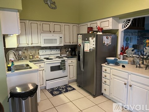 A kitchen with white cabinets and a black fridge.