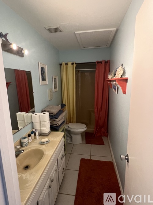 A bathroom with a sink, mirror, toilet, and shower.