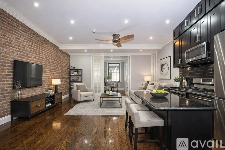 A modern kitchen with black cabinets and a brick wall.