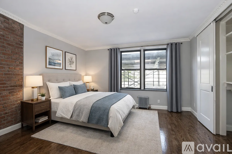 A bedroom with a large bed and a window with grey curtains.