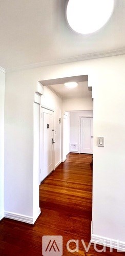 A hallway with wooden floors and white walls.
