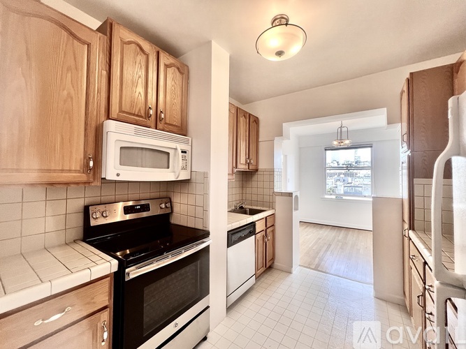 A kitchen with wooden cabinets and a white tiled floor.