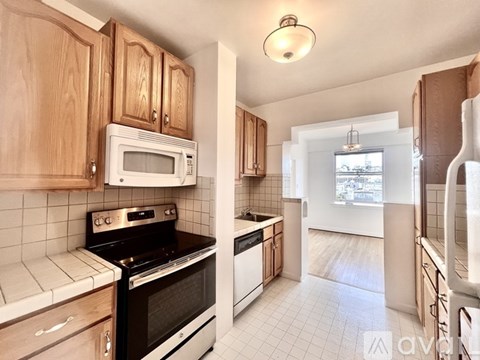 A kitchen with wooden cabinets and a white tiled floor.