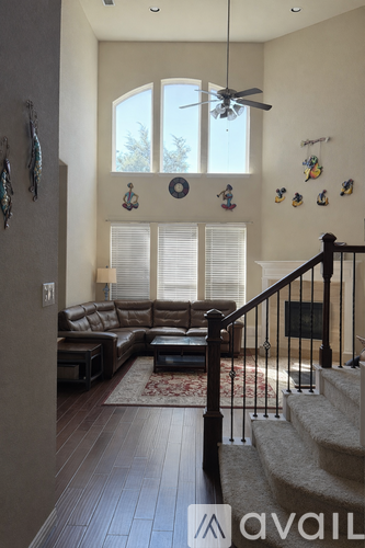 A living room with a brown leather couch and a staircase.