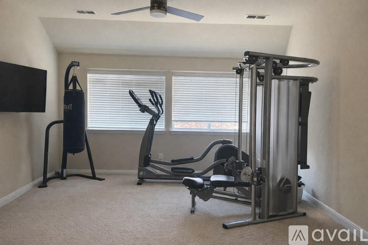 A home gym with a treadmill, weights, and a television.