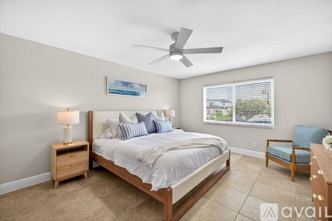 A bedroom with a bed, a chair, and a ceiling fan.