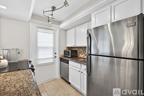 A kitchen with a stainless steel refrigerator and granite countertops.