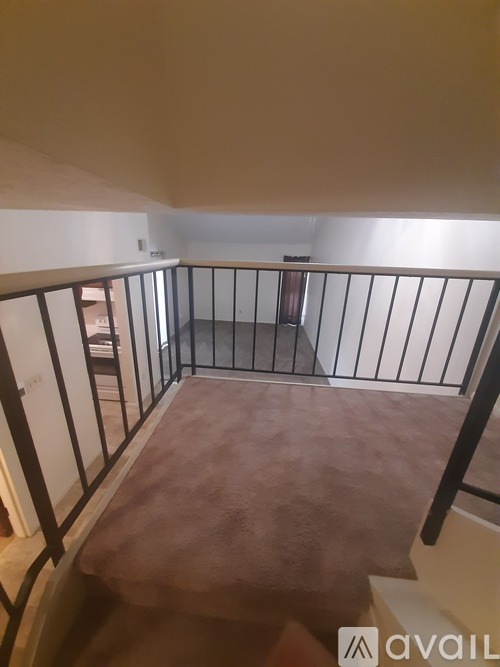 A balcony with a metal railing and a brown carpet.