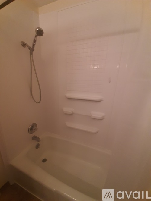 A white bathtub with a shower head and a shower hose.