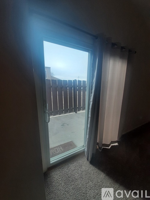 A room with a carpeted floor and a glass door leading to a balcony.