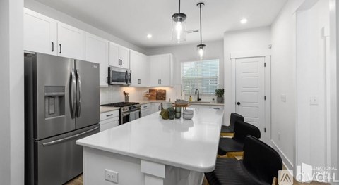 A modern kitchen with a white island and stainless steel appliances.