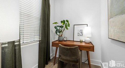 A room with a desk, chair, and a plant.