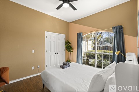 A bedroom with a white bed and a ceiling fan.