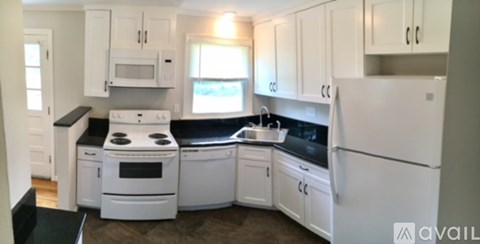 A kitchen with white appliances and cabinets.