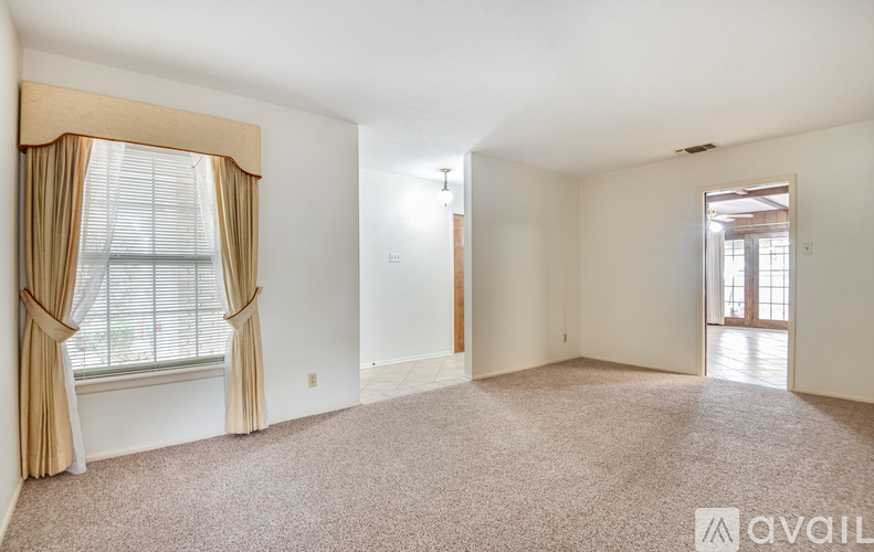 A spacious room with a window and carpeted floor.