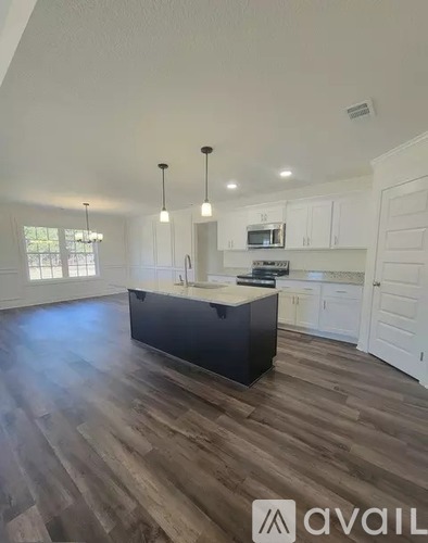 A kitchen with a black island and white cabinets.