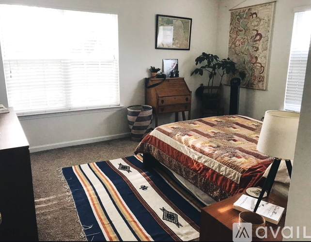 A bedroom with a bed, desk, and window.