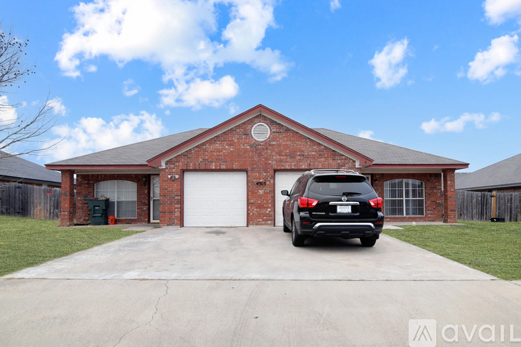A black SUV is parked in front of a red brick house.