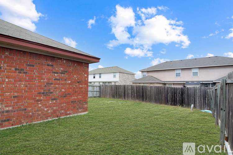 A backyard with a wooden fence and a red brick building.