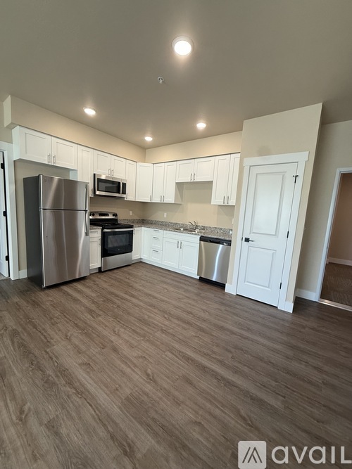 A kitchen with white cabinets and a wooden floor.