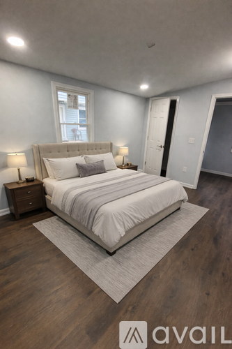 A bedroom with a large bed and a nightstand with a lamp.