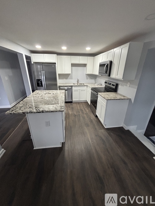A kitchen with white cabinets and a granite countertop.