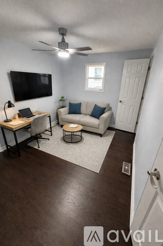 A living room with a couch, chair, and a television mounted on the wall.