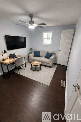 A living room with a couch, chair, and a television mounted on the wall.