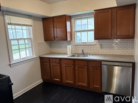 A kitchen with wooden cabinets and a stainless steel dishwasher.
