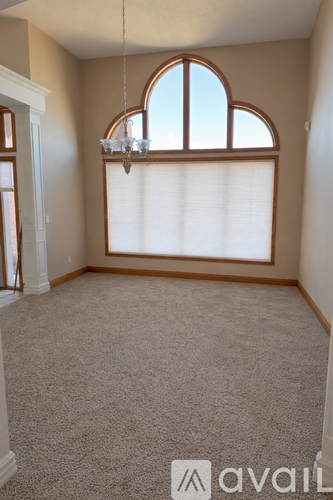 A room with a carpeted floor and a large window with blinds.