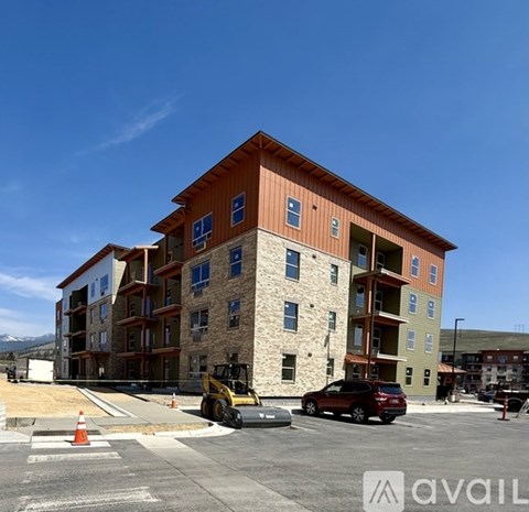 A construction site with a building under construction and a red car parked in front.