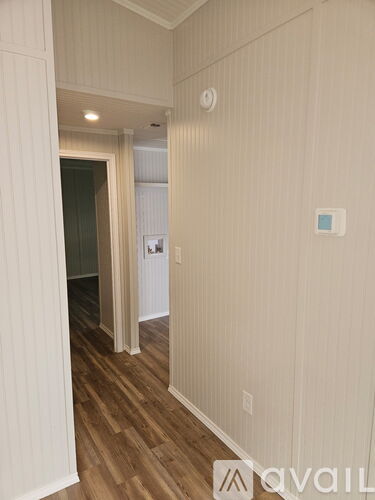 A hallway with wood floors and white walls.