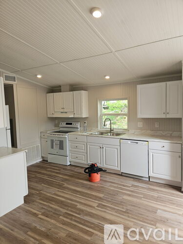 A kitchen with white cabinets and a wooden floor.