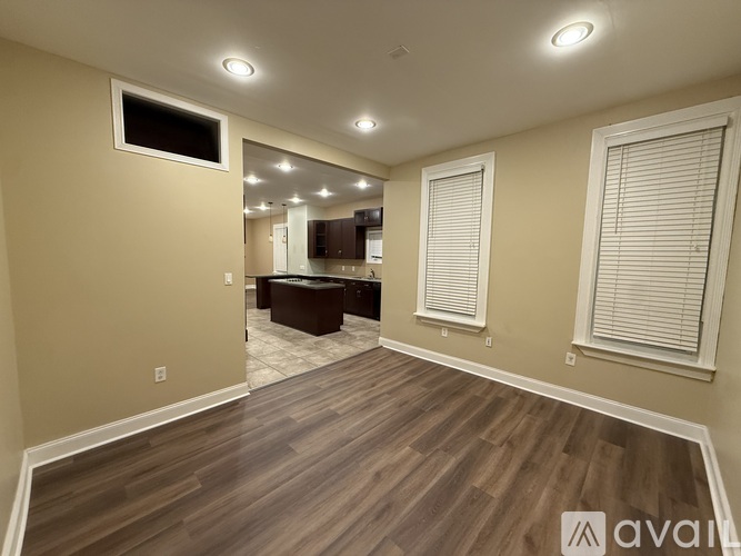 A spacious room with wooden flooring and a television on the wall.