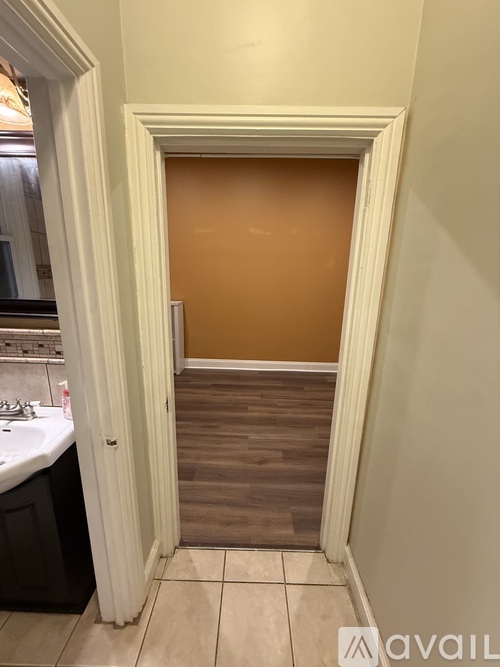 A bathroom with a white door and brown floor.