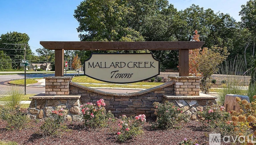 A wooden sign that says "Mallard Creek Town" in front of a grassy area.