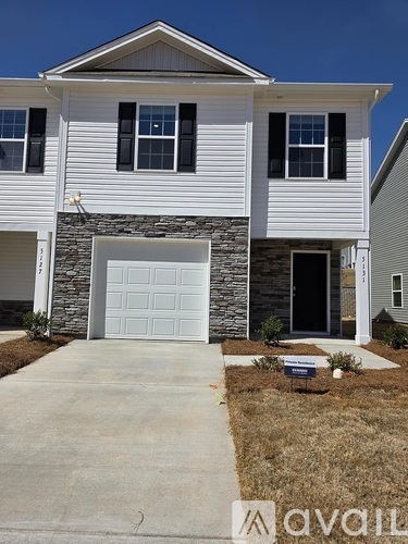A two-story house with a garage door and a stone pillar.
