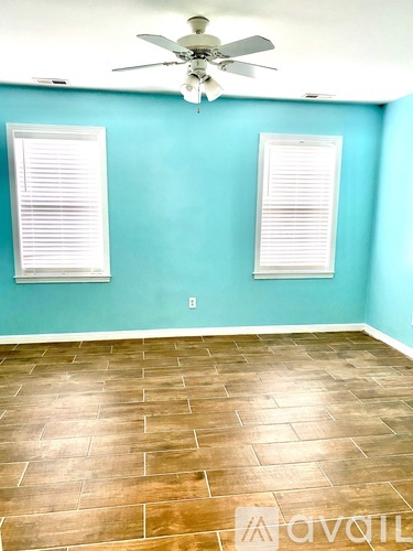 A room with a ceiling fan and two windows.