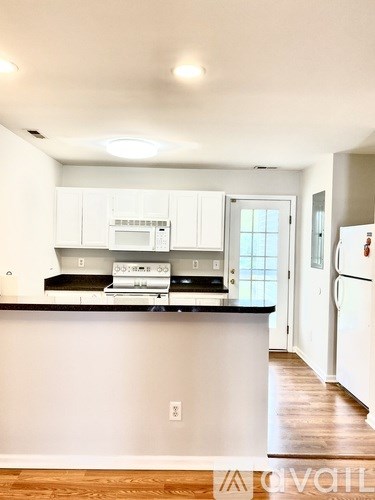 A kitchen with white cabinets and a black countertop.